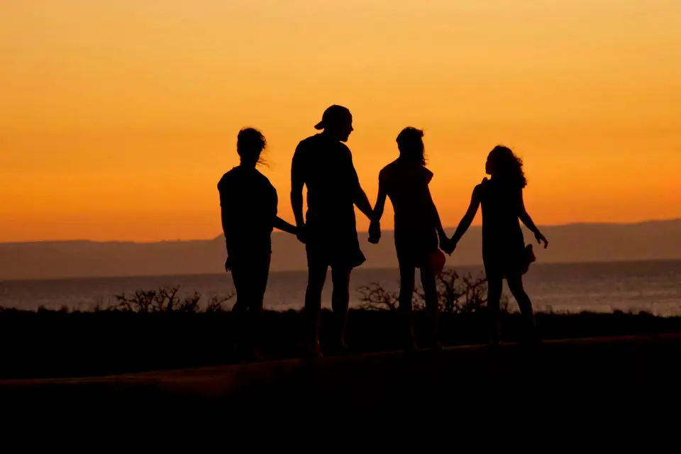 A family silhouetted against a low evening sun